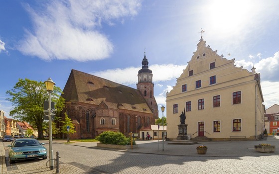 Marktplatz mit Backsteinkirche, hellem Giebelhaus, Statue, Kopfsteinpflaster und blauem Himmel mit Wolken., Foto: Andreas Franke, Lizenz: Andreas Franke