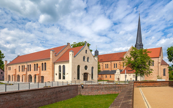 Wei&szlig;es Schloss mit roten Ziegeld&auml;chern, Stufengiebeln und gr&uuml;nem Turm vor wolkigem Himmel; Baum im Vordergrund., Foto: Andreas Franke, Lizenz: Andreas Franke